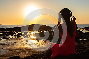 Girl in headphones listening to music in the city at sunset.