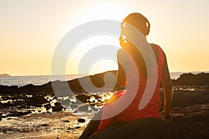 Girl in headphones listening to music in the city at sunset.