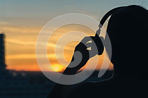 Girl in headphones listening to music in the city at sunset