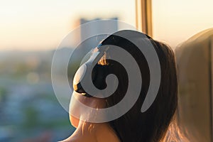 Girl in headphones listening to music in the city at sunset