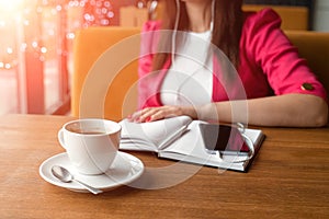 Girl in headphones listening to music sitting in cafe. Break, business lunch, diary