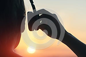 Girl in headphones listening to music in the city at sunset