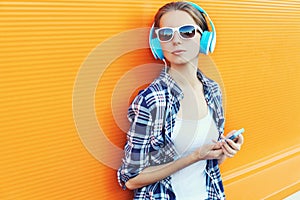 Girl in headphones listens to music using smartphone over colorful