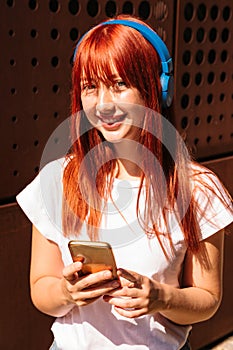 Girl with headphones looks at camera and smiles