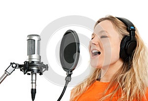 Girl in headphones singing with studio microphone