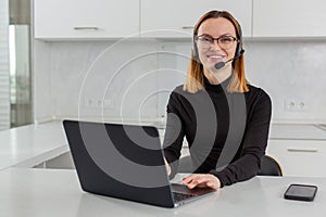 girl in a headset and headphones works in a call center behind a laptop