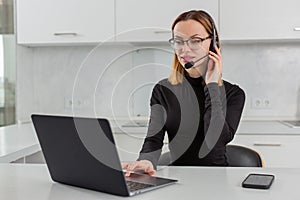 girl in a headset with a microphone works in a call center sitting at a laptop