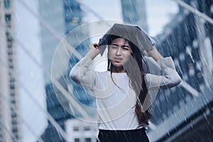 Girl in the heavy rain storm cover head with newspaper for economic obstacle