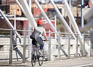 The girl in the helmet rides bicycle over the bridge in hurry to the university