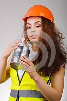 Girl in a helmet and vest looks into the open metal container.