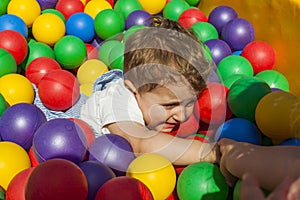 Girl helping her little brother getting out a ball pool