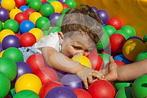 Girl helping her little brother getting out a ball pool
