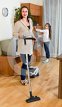 Girl helping mom to clean furniture