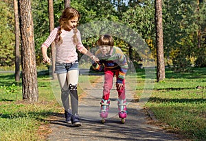 The girl helps the boy to roller-skate.