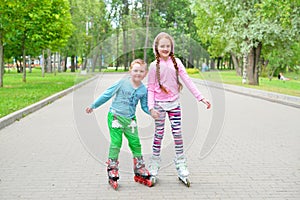 The girl helps her younger brother to roller skate in the Park