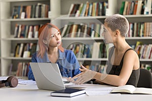 Girl helps with task to serious, attentive red-haired schoolmate