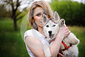 A girl and her dog husky walking in a park.