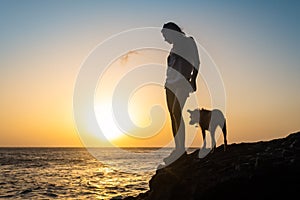 Girl with her dog at sunset on the sea