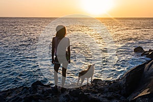 Girl with her dog at sunset on the sea