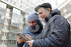 Girl and her father with a tablet in hands looking for right way in city