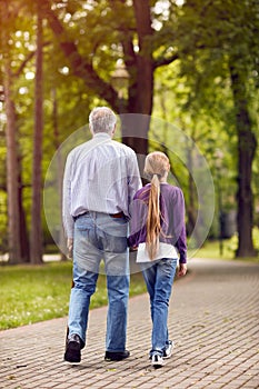 Girl and her grandfather holding hands on walk