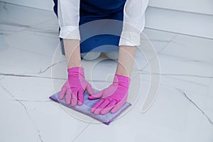 The girl is on her knees. Hands wearing pink gloves for cleaning, Floor cleaning with hands.