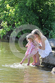 Girl and her little daughter squirting water at the lake