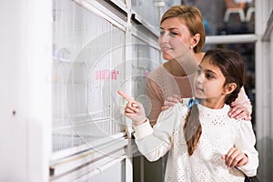 Girl with her mother buying bird in pet store