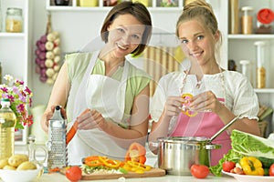 Girl with her mother cooking together at kitchen