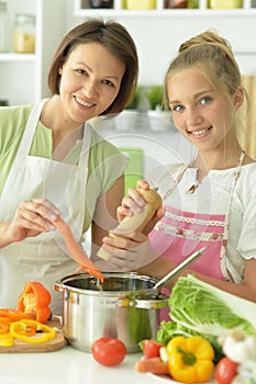 Girl with her mother cooking together at kitchen