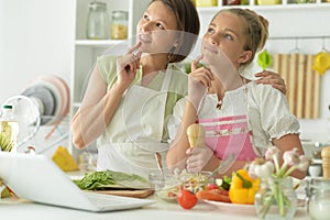 Girl with her mother cooking together at kitchen table