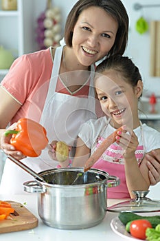 Girl with her mother cooking together at kitchen table