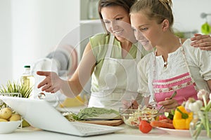 Girl with her mother cooking together at kitchen table