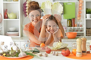 Girl with her mother cooking together at kitchen table