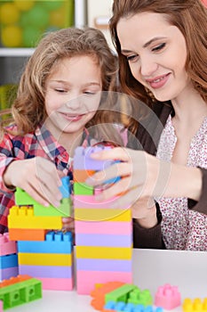 Girl and her mother playing colorful plastic blocks