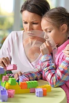 Girl and her mother playing with colorful plastic blocks
