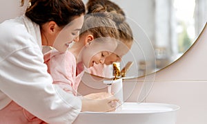 girl and her mother are washing hands