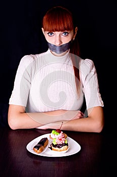 Girl with her mouth sealed with adhesive tape and cakes