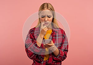 Girl with her smartphone. scared and afraid expression. Pink background