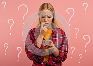 Girl with her smartphone. scared and afraid expression. Pink background