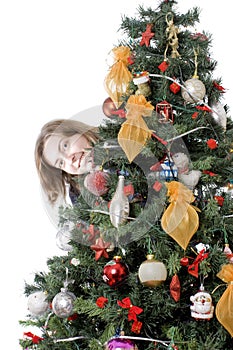 Girl hiding behind christmas tree