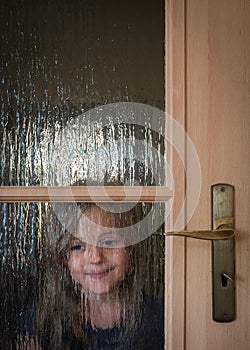 Girl hiding behind doors at home