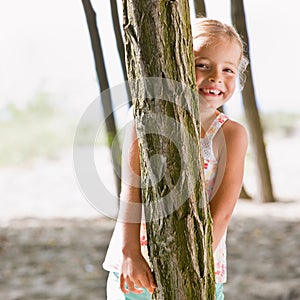 Girl hiding behind tree