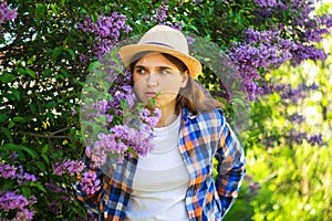 Girl hiding outside. Defocus beautiful young woman near blooming spring tree. Bush lilac flowers. Youth, love, fashion, romantic,