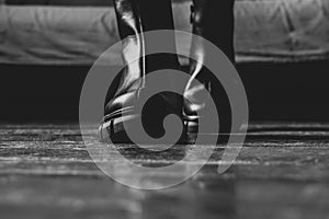 Girl in high black boots on the old dirty floor at home, women`s shoes, feet in shoes on the floor, shoes