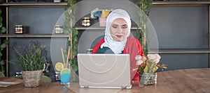 Girl with hijab typing on laptop and relaxing