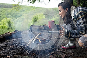 A girl on a hike blows up a fire to keep warm