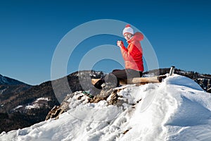 Girl hiker relaxing and looking on snowy mountains from top of the hill during winter