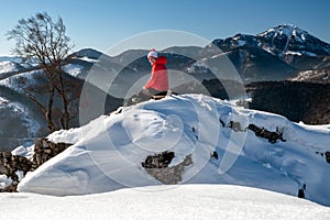 Girl hiker sitting on ruins of castle Liptovsky hrad covered by snow during winter