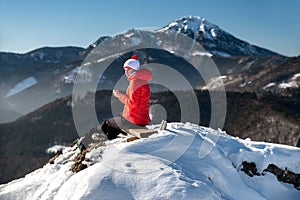 Girl hiker sitting on ruins of castle Liptovsky hrad covered by snow during winter